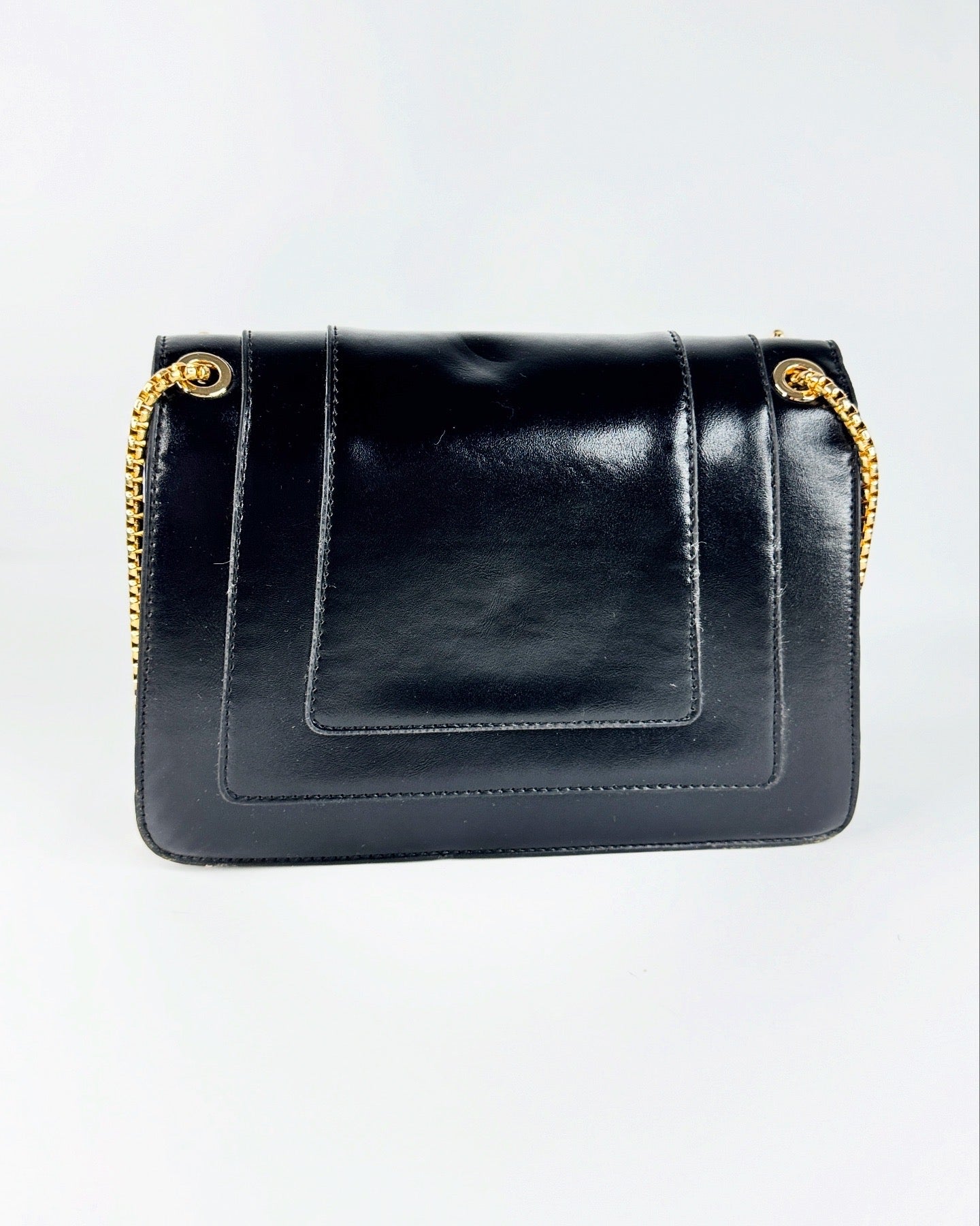 Sac à bandoulière noir en cuir lisse avec chaîne dorée et fermoir tête de serpent